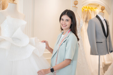 Obraz premium Beautiful female designer looking to camera with attractive smile at wedding studio.