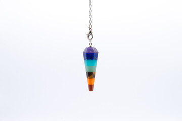 Seven Chakra color crystal pendulum on chain isolated on white background.