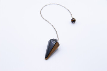Tiger's eye crystal pendulum on chain isolated on white background.