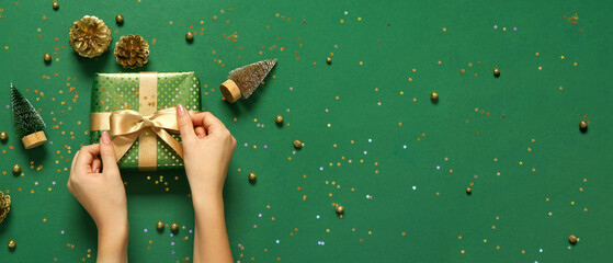 Female hands packing Christmas gift on green background with space for text, top view