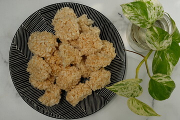 Rengginang is a typical Indonesian snack made from glutinous rice grains that are seasoned and fried. Served on a bamboo container on a wooden table. Indonesian food. Camilan gurih.