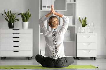 Young businesswoman doing yoga in office. Concept of healthy spine