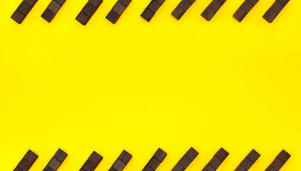 斜めに並べた黒いウッドキューブの縞模様が上下に並ぶ黄色い背景