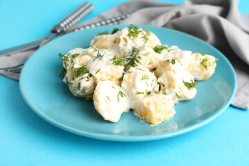 Plate of tasty Potato Salad with greens on blue background, closeup