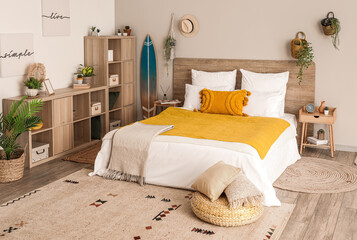 Interior of light bedroom with surfboard, houseplants and shelving unit