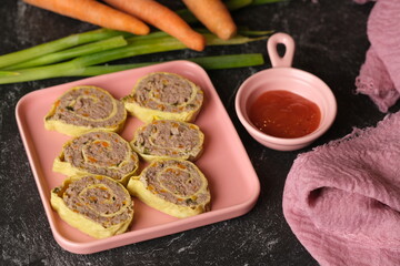 Rolade Daging Sapi. Beef roulade on a square pink ceramic plate. Made from ground beef, pepper, nutmeg, eggs, garlic, carrot, onion leaves. Served with tomato sauce.