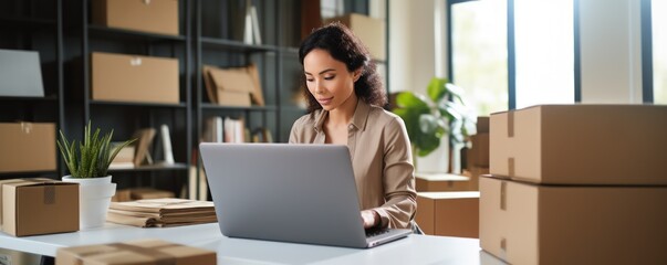 Online store seller during an online video call with a buyer. A young Asian woman in front of laptop monitor in a warehouse of packaged products