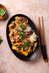 Asian pork with vegetables and funchose on a black plate top view vertical photo