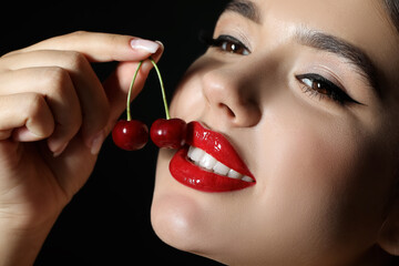 Beautiful woman with red lips and cherries on dark background, closeup - obrazy, fototapety, plakaty