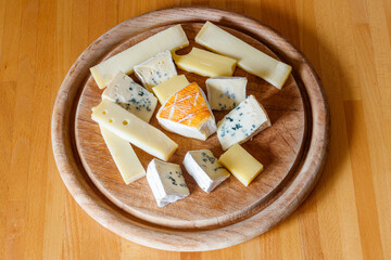 Cheese platter with different kinds of cheese on wooden table