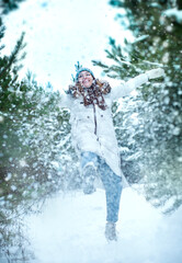 girl playfully kicking snow in the forest in winter