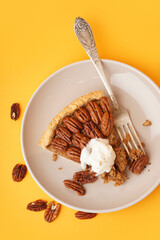 Plate with piece of tasty pecan pie on yellow background