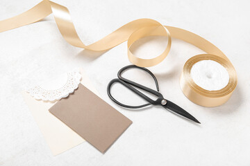 Golden satin ribbon, scissors and greeting card on white background