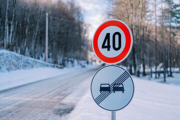 Road sign with speed limit on a snowy road in the park. Caption: 40
