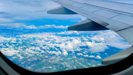 Obraz na płótnie Canvas Aerial view of sky and clouds through an airplane window. Travel concept. traveler, trip, vacation, tourism, landscape, vibrant, nature, scenery, background