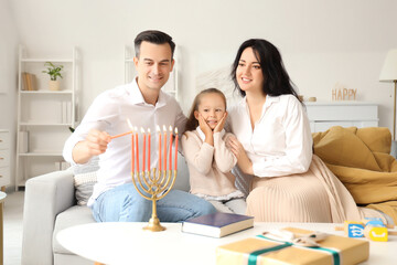 Happy family lighting candles for Hanukkah at home