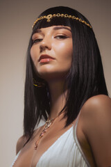 Queen Cleopatra studio beauty portrait. Young adult fashion woman with perfect makeup and stylish straight bob haircut wig, wearing fashionable golden jewelry. High quality conceptual photo for beauty