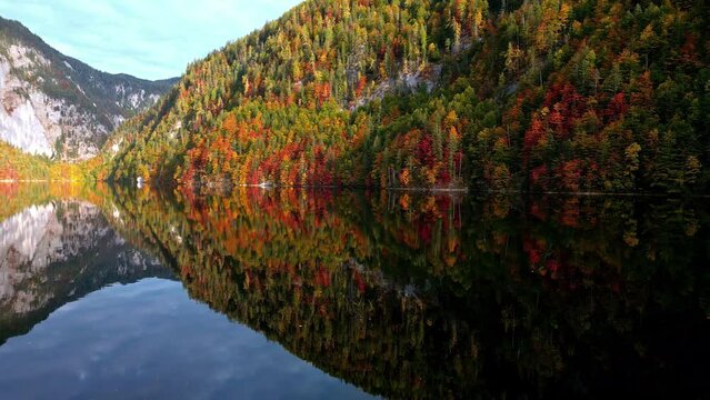 Drone shot over mirroring waters of the Toplitzsee lake, autumn foliage in Austria