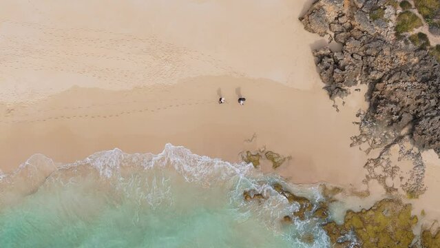 Couple walking along the Cape to Cape hiking trail in Yallingup, Western Australia through rocky beach section
