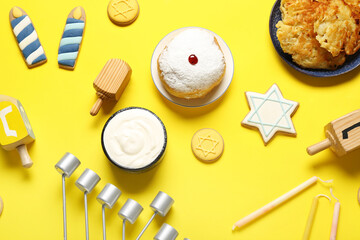 Hannukah composition with menorah, donut and dreidels on yellow background