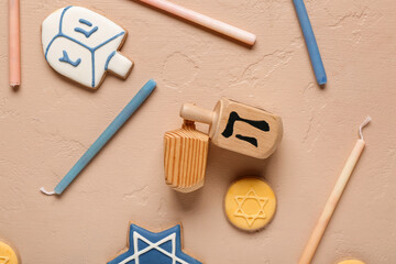 Hannukah composition with dreidels, candles and cookies on beige table