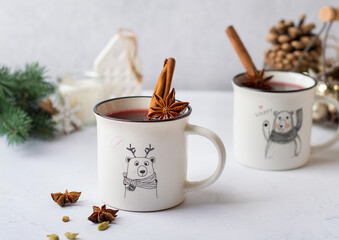 Obraz na płótnie Canvas Celebrating, celebrating Christmas, New Year, preparing mulled wine. Cups with a pattern of red wine and spices, cinnamon, star anise, New Year decorations, decor. Light composition, horizontal.