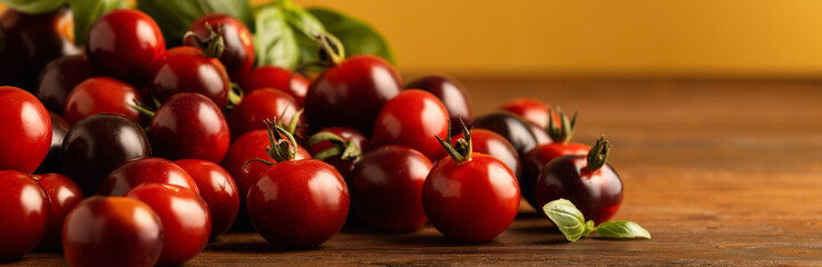 Banner Black cherry tomatoes and basil on a wooden table