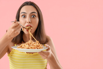 Young woman eating tasty pasta on pink background, closeup