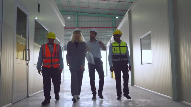 Group of engineer or factory worker survay in factory together. They engineers discussing plans and work while walking together. Employee high five with teamwork, logistic and industrial concept.