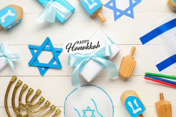 Hanukkah composition with gift box, Israel flag, dreidels and menorah on white wooden background