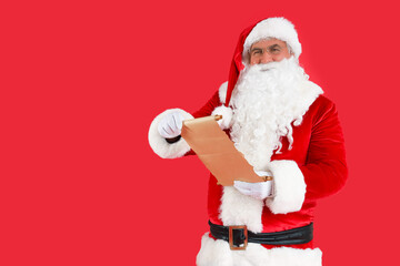 Santa Claus with wish list on red background