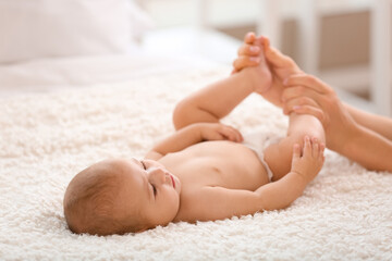 Fototapeta na wymiar Mother massaging her baby's feet in bedroom, closeup