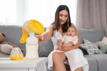Mother with her baby taking breast pump at home, closeup