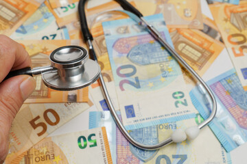 stethoscope with euro banknotes in the background, health care costs concept
