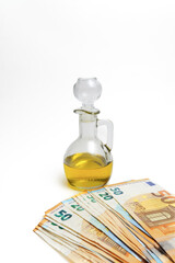 euro banknotes in front of a bottle of olive oil isolated on a white background, oil price rise...