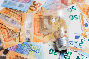 light bulb on a pile of euro banknotes, electricity price increase concept