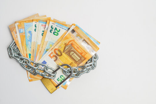 pile of euro banknotes tied with a chain and a padlock isolated on a white background