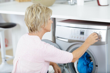 senior woman loading washing machine at home