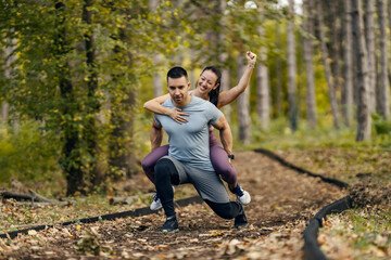 A sportsman is carrying his partner on the backs and doing lunges in nature.