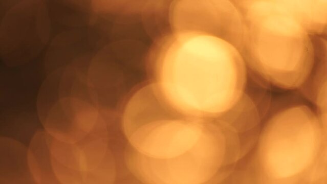 Blurred golden sea at sunset. The sun reflects and sparkles on the waves with bokeh, illuminating the golden sea. Holiday recreation concept. Abstract nautical summer ocean sunset nature background