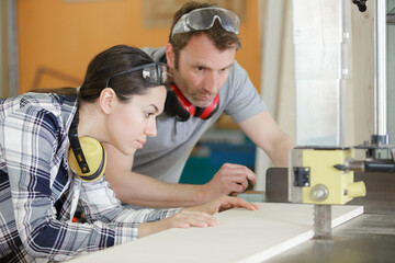 busy and serious craftswoman grinding timbers with special machine