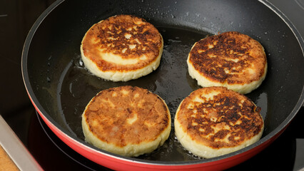 Delicious cottage cheese fritters are fried in a pan close up. Process of cooking homemade food. Preparing healthy tasty breakfast cheese cakes. Russian, Ukrainian, Belorussian cuisine.