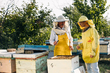 Young woman is learning about beekeeping from her grandfather.