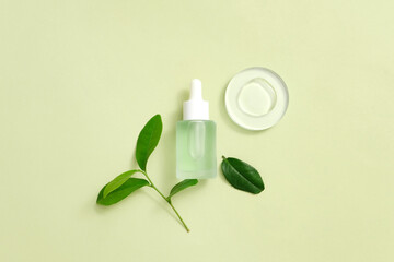 Obraz na płótnie Canvas Organic serum with fresh green tea leaves, liquid drops displayed on a transparent platform, pastel background. Minimalist concept with beauty products.