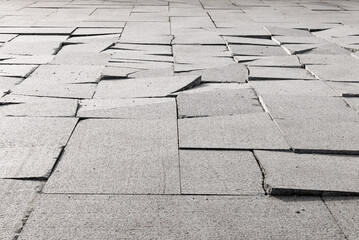 Broken pavement made of granite slabs. Selective focus.