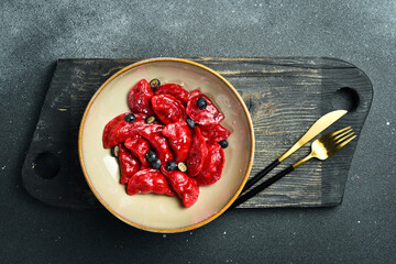 Dumplings with cherries, raspberries and salted caramel. On a black stone background. In a plate,...