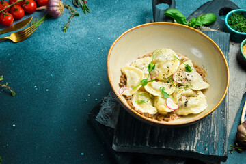 Dumplings with potatoes and mushroom sauce. On a black stone background. In a plate, close-up.