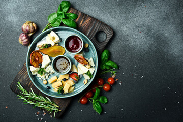 Sliced cheese on a plate. Assortment of cheeses. close up On a black stone background.