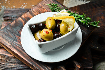 Olives in a white bowl. Appetizer. On a dark stone background. Free space for text.