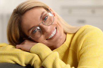 Happy woman in stylish glasses on sofa indoors